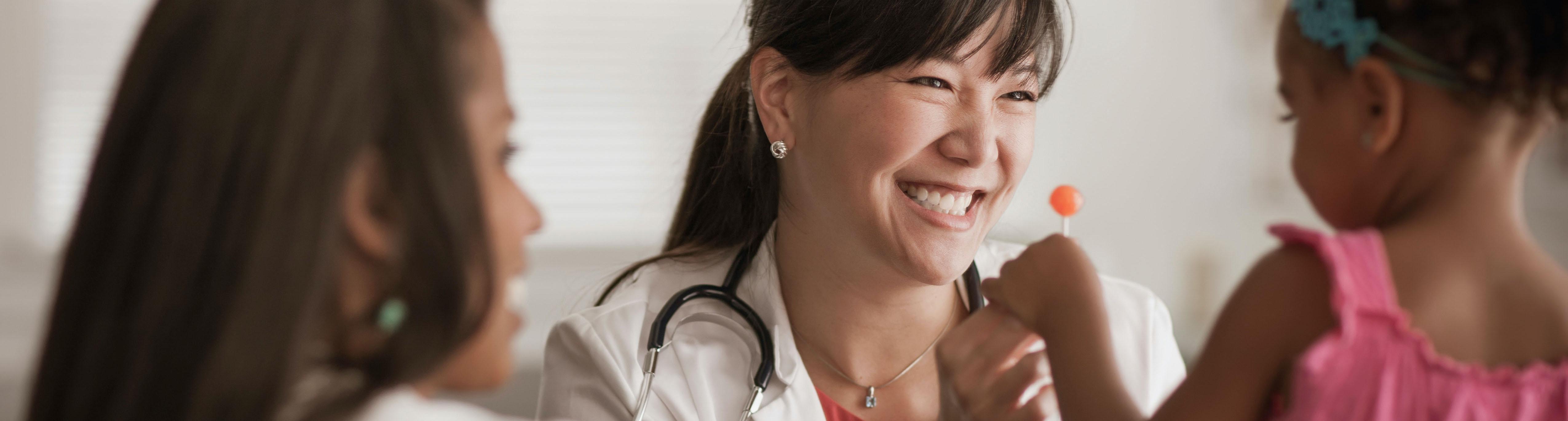 Smiling doctor handing a lollipop to a child